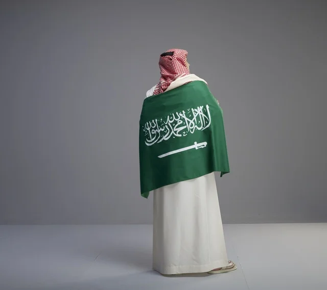 Saudi Man Wrapped in National Flag Back View