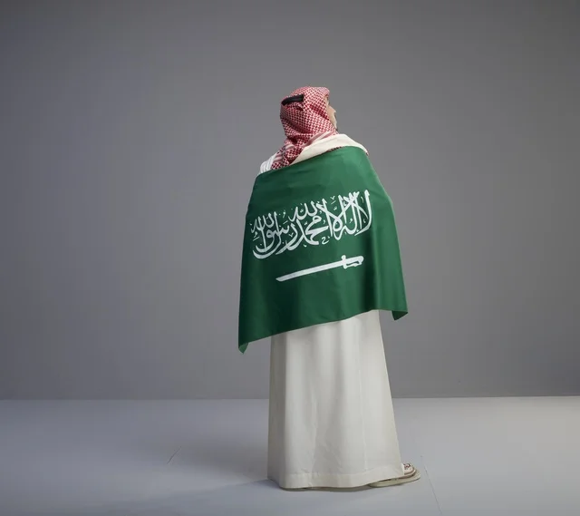 رجل سعودي يحمل العلم الوطني رؤية خلفية