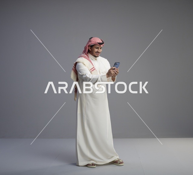 رجل سعودي يستخدم الهاتف الذكي بالزي التقليدي