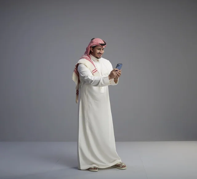رجل سعودي يستخدم الهاتف الذكي بالزي التقليدي
