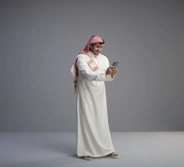 Saudi Man in Traditional Thobe Using Smartphone
