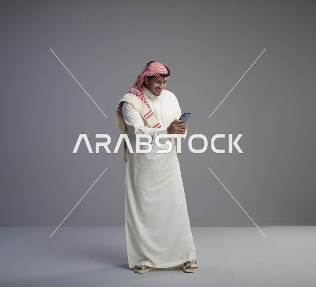 Saudi Man Using Smartphone on Gray Background