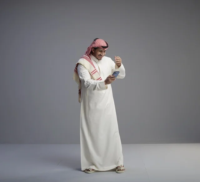 Saudi Man in Thobe Using Smartphone Studio Portrait