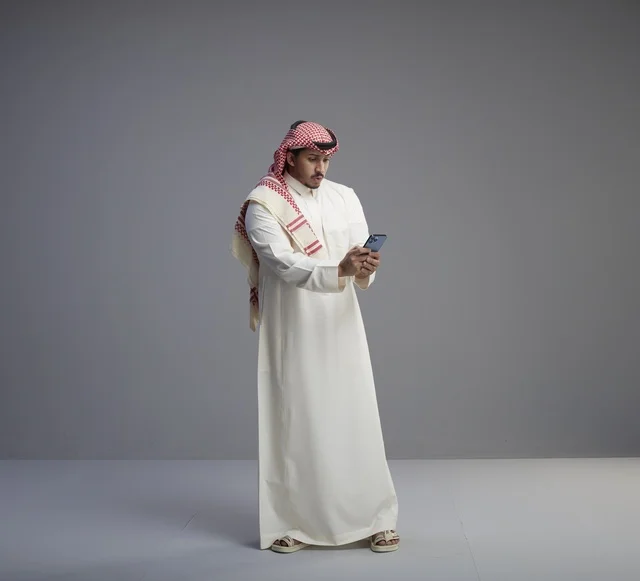 Saudi Man in Traditional Thobe Using Smartphone