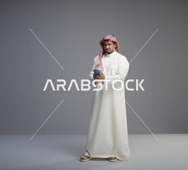 Saudi Man Using Smartphone on Grey Background
