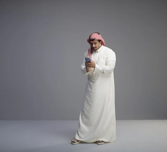 Saudi Man in Traditional Thobe Using Smartphone Studio