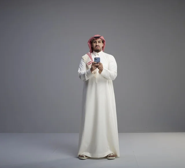 Saudi Man in Traditional Thobe Using Smartphone