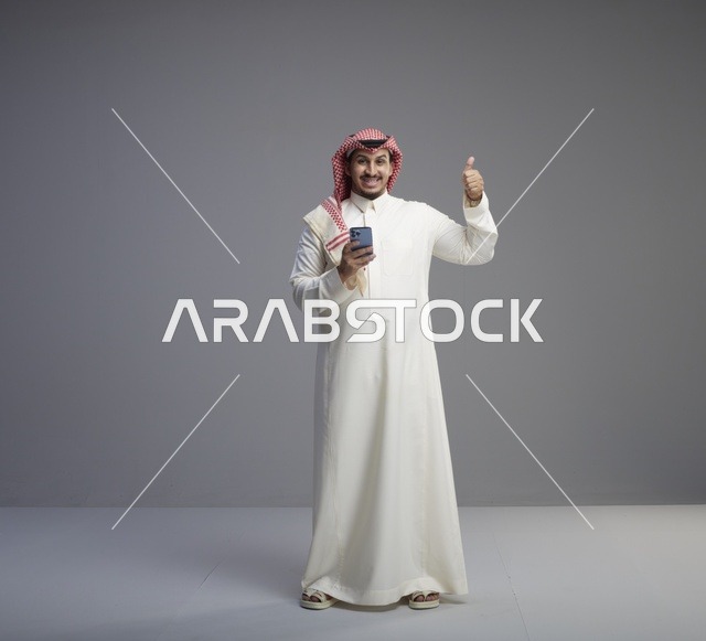 رجل سعودي يستخدم هاتف ذكي وإيماءة الإبهام
