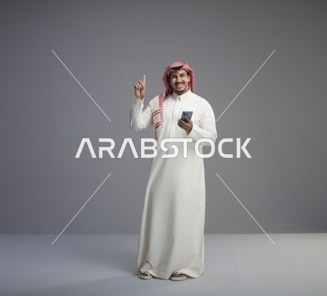 رجل سعودي مع هاتف ذكي يشير للأعلى