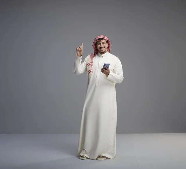 Saudi Man with Smartphone Pointing Up in Studio
