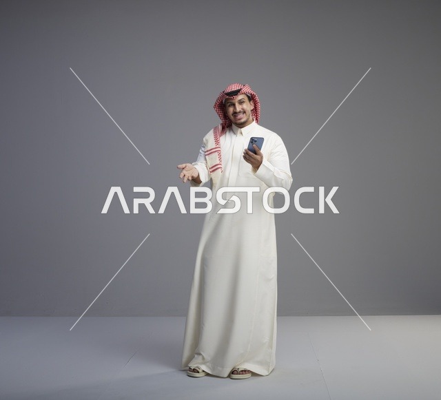 رجل سعودي يحمل هاتف ذكي في استوديو