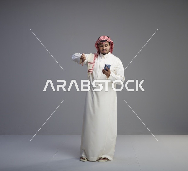 رجل سعودي يستخدم الهاتف الذكي مع إشارة عدم الإعجاب