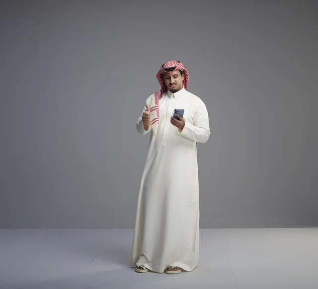 رجل سعودي يستخدم الهاتف الذكي مع علامة الإعجاب