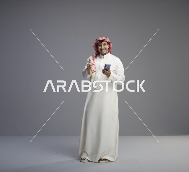 رجل سعودي مع هاتف ذكي وعلامة إعجاب في الاستوديو