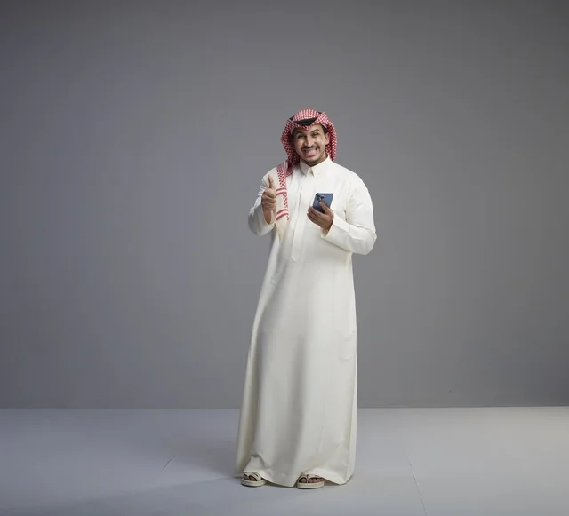 Saudi Man with Smartphone Giving Thumbs Up in Studio