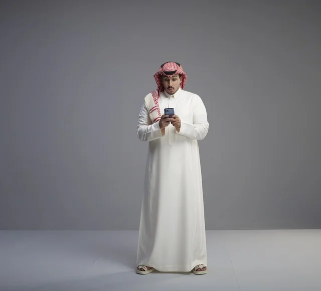 Saudi Man Using Smartphone in Studio Grey Background
