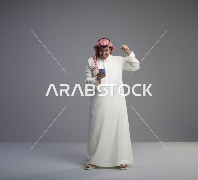 رجل سعودي يستخدم الهاتف الذكي بإيماءة نصر في استوديو