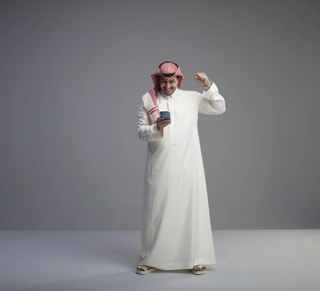 رجل سعودي يستخدم الهاتف الذكي بإيماءة نصر في استوديو