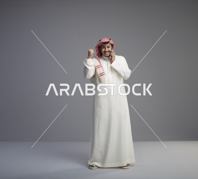رجل سعودي يتحدث بالجوال في الاستوديو احتفالاً بالنجاح