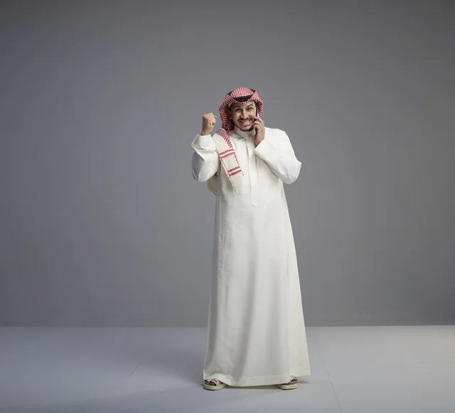 رجل سعودي يتحدث بالجوال في الاستوديو احتفالاً بالنجاح