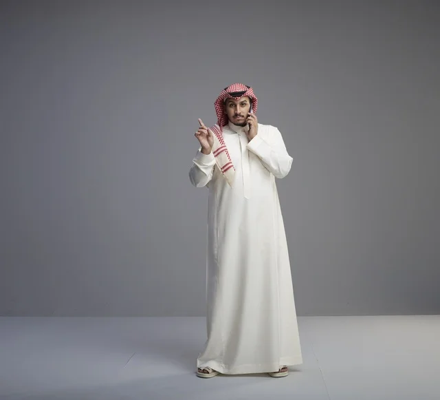 رجل سعودي بالثوب التقليدي يتحدث عبر الهاتف الذكي