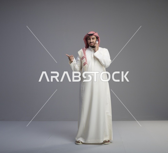 رجل سعودي يتحدث عبر الهاتف الذكي في الاستوديو