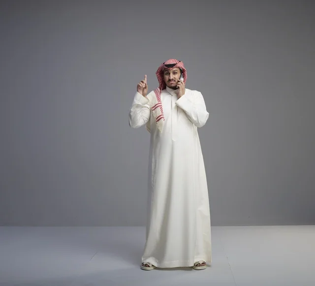 Saudi Man Talking on Smartphone in Grey Studio Setting