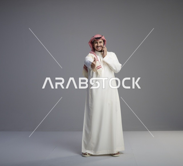 رجل سعودي يتحدث بالهاتف الذكي مع إشارة الإعجاب