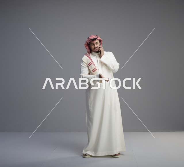رجل سعودي يتحدث عبر الهاتف الذكي في الاستوديو
