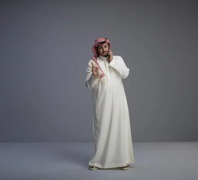 رجل سعودي بالزي التقليدي يتحدث عبر الهاتف الذكي