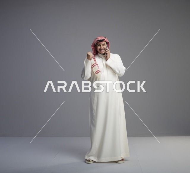 رجل سعودي يتحدث بالهاتف الذكي مع إيماءة النصر