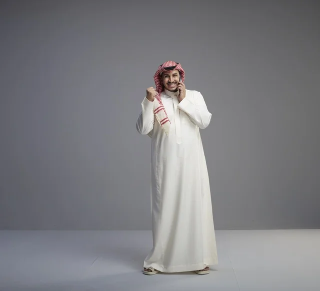 رجل سعودي يتحدث بالهاتف الذكي مع إيماءة النصر
