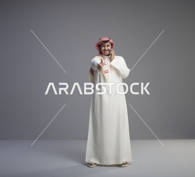 رجل سعودي يتحدث بالهاتف الذكي ويشير بالإعجاب