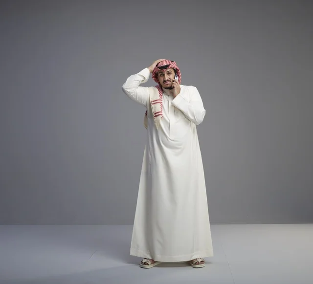 Saudi Man in Traditional Thobe Worried on Smartphone