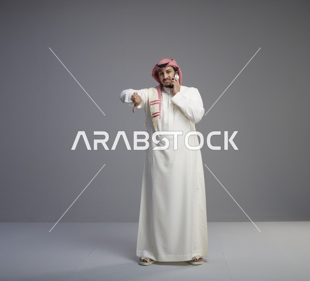 رجل سعودي يتحدث بالهاتف الذكي وينظر لساعة اليد