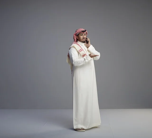 رجل سعودي يتحدث عبر الهاتف الذكي في الاستوديو
