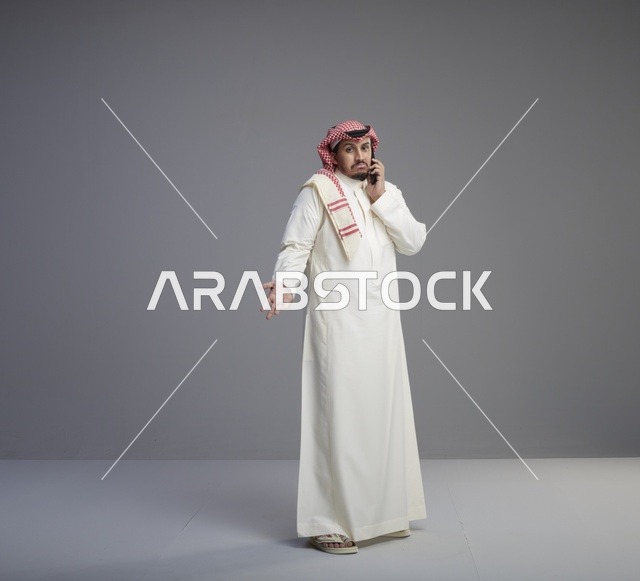 رجل سعودي يتحدث عبر الجوال بالثوب التقليدي في استوديو