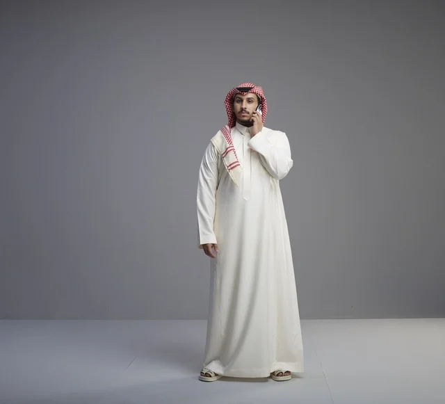 Saudi Man in Traditional Thobe Talking on Smartphone
