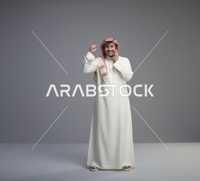 رجل سعودي يتحدث بالهاتف الذكي ويحتفل بالنجاح في استوديو