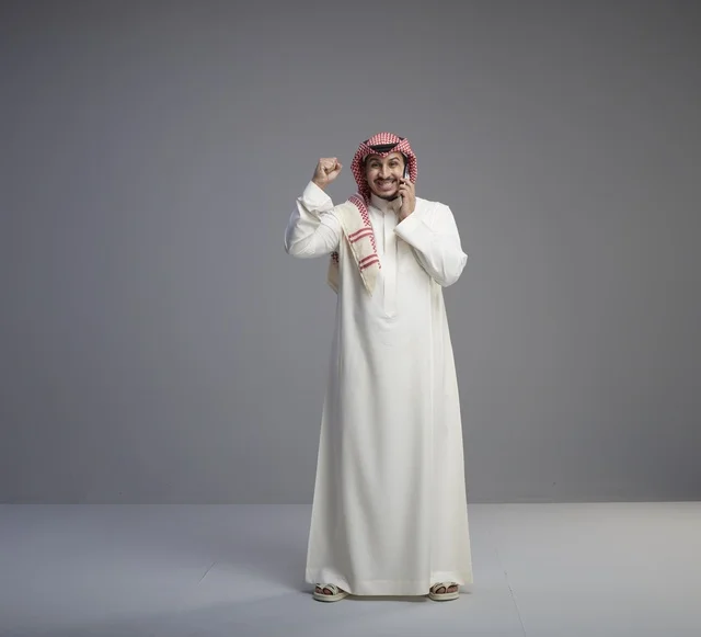 رجل سعودي يتحدث بالهاتف الذكي ويحتفل بالنجاح في استوديو