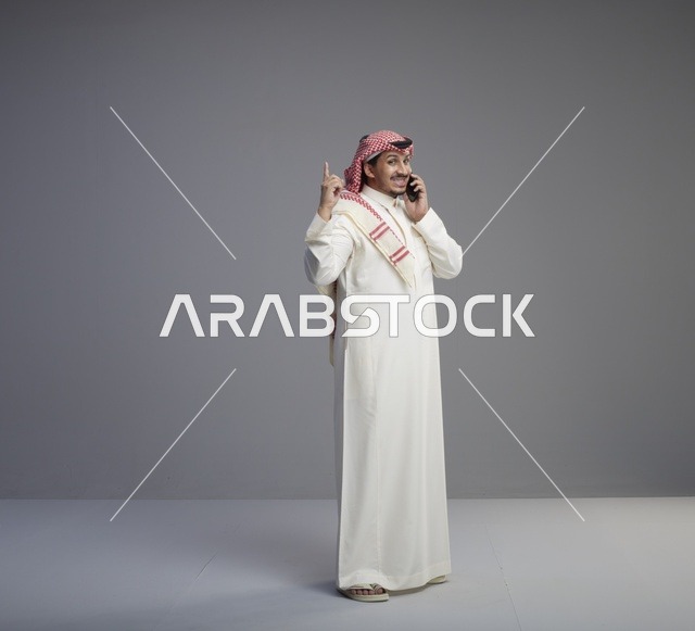 رجل سعودي يتحدث بالهاتف الذكي بالثوب التقليدي