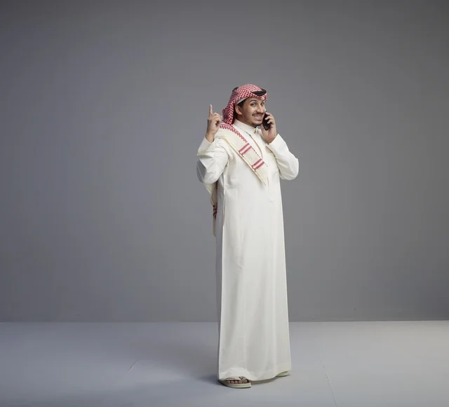 رجل سعودي يتحدث بالهاتف الذكي بالثوب التقليدي