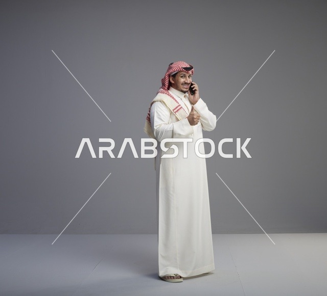 رجل سعودي يتحدث بالهاتف الذكي مع إشارة الإبهام