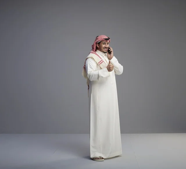 رجل سعودي يتحدث بالهاتف الذكي مع إشارة الإبهام