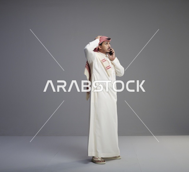 رجل سعودي يتحدث عبر الجوال بخلفية رمادية