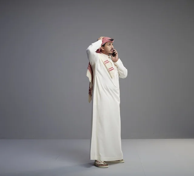 Saudi Man Talking on Smartphone Against Grey Background