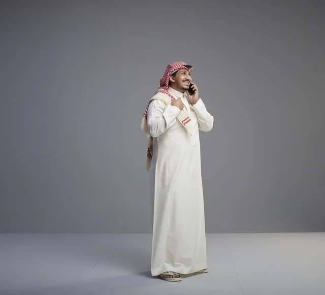 رجل سعودي يتحدث عبر الهاتف الذكي في الاستوديو