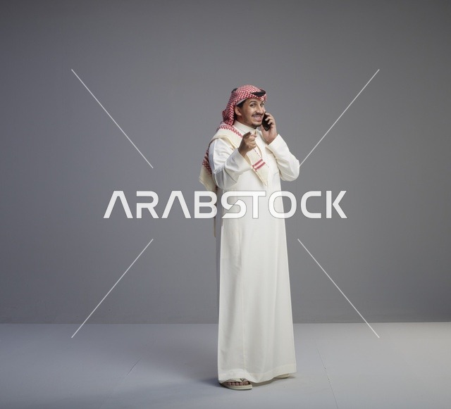 رجل سعودي يتحدث بالهاتف الذكي بالثوب التقليدي