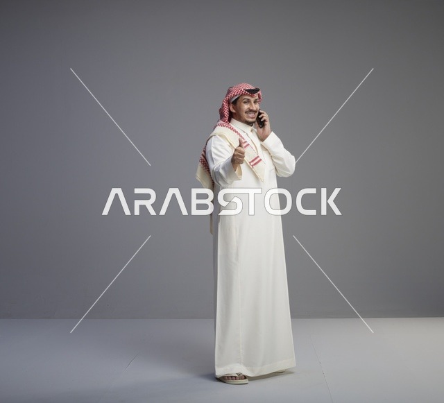 رجل سعودي يتحدث بالهاتف الذكي مع إيماءة الإعجاب