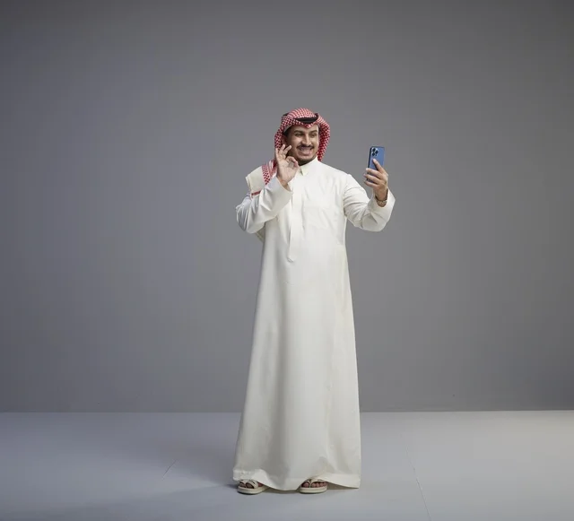 رجل سعودي يستخدم الهاتف الذكي بخلفية رمادية